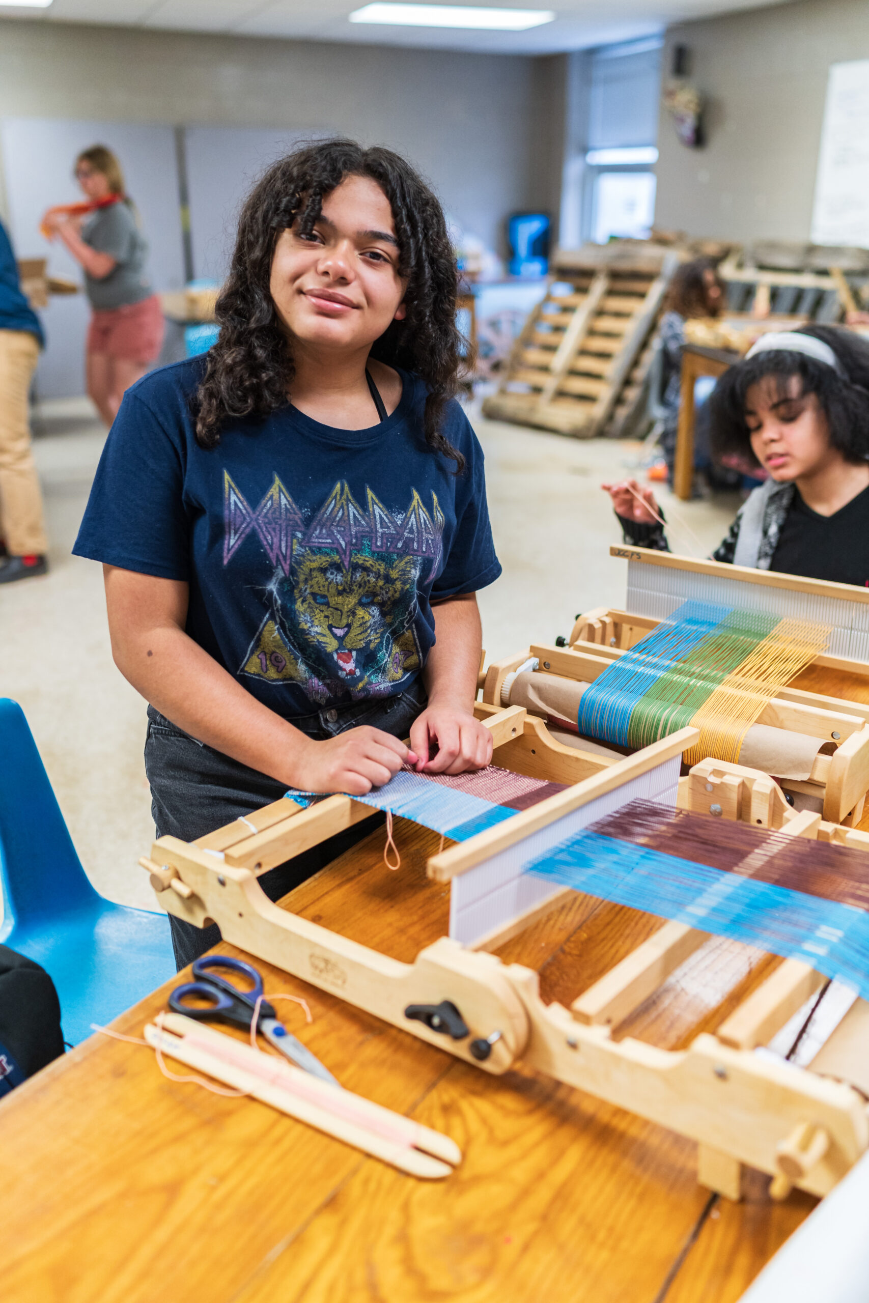 Middle schooler weaving on loom.